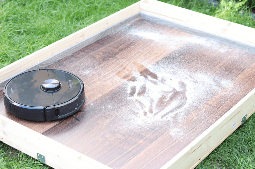 The Roborock S6 in the test arena removing sand from a hardwood floor